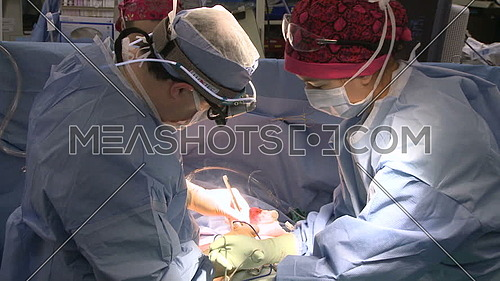 medium shot for operation room while a Nurse assists surgeon during procedure 