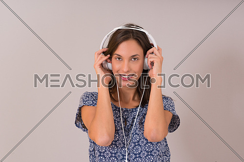 Happy young woman listening and enjoying music with headphones isolated on a white background