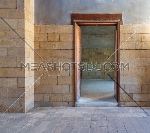 Open wooden door in bricks stone wall revealing vacant room with bricks wall, Old Cairo, Egypt