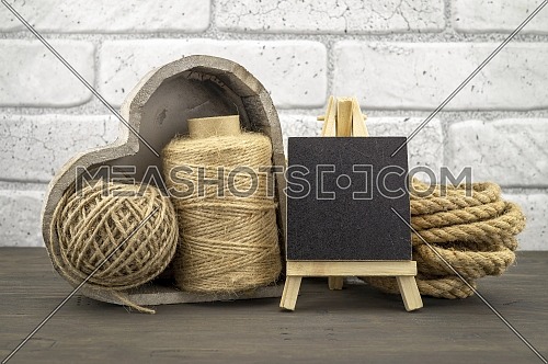 Assorted balls of hemp twine and string with skeins of rope and slate chalkboard in a close up rustic still life