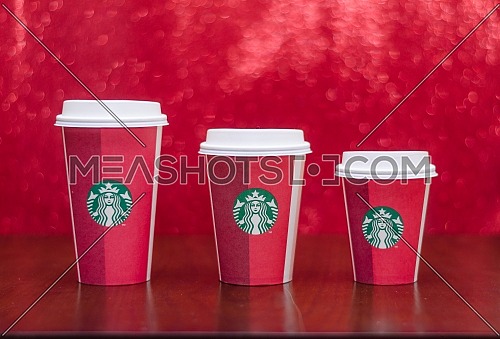 Starbucks takeaway paper cup, in special design for Christmas on a festive red background; December 2018 - Cairo, Egypt.