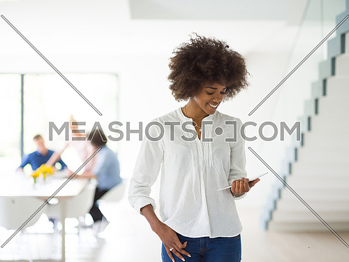 african american Businesswoman using tablet with coworkers in backgorund having meeting