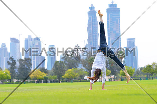 pretty healthy young woman jump and exercise fitness on grass in green park with city in background