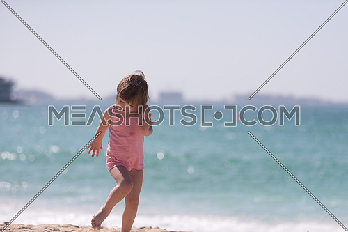 happy little girl at the seaside in the summer.Adorable little girl at beach during summer vacation. Happy baby by the sea or ocean