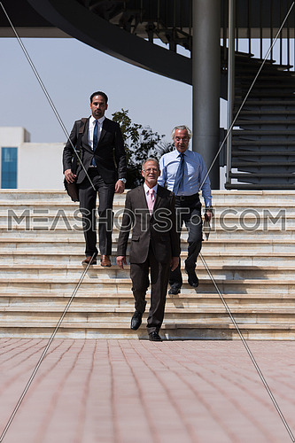 Group of business executives walking in front of a corporate building
