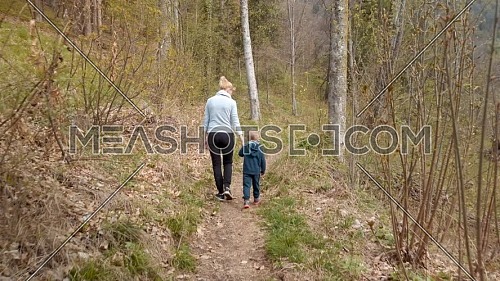 Rear view of mother and her son walking in a mountain path