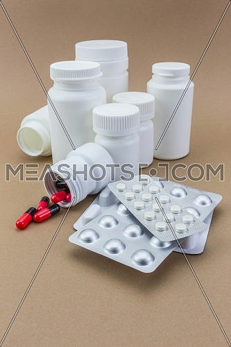 Pills spilling from an open bottle on brown background