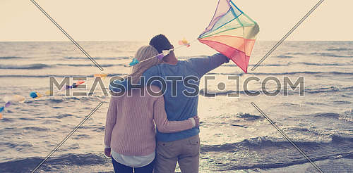 Loving Couple Flying A Kite at Beach and having fun on autumn day