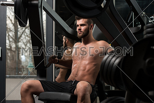 Handsome Man Is Working Out Chest On Machine In A Modern Gym
