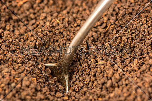 A spoon inserted between black tea particles
