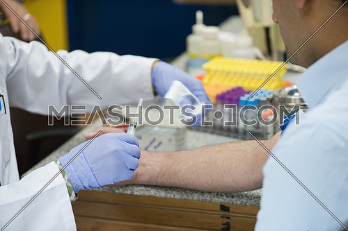 Young middle eastern Medical technologist doing a blood draw services for patient.