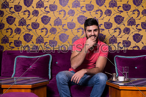 Young Man Drinking Coffee In The Cafe Bar With Colorful Walls On Background