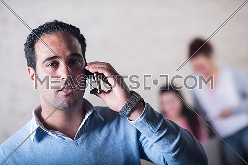 Young casual middle eastern businessman talking on the phone in modern stylish office with smile