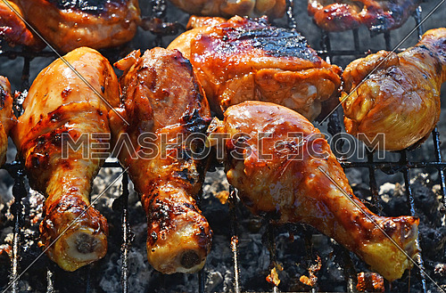Grilled barbeque chicken legs meat portions cooked on fire grill close up