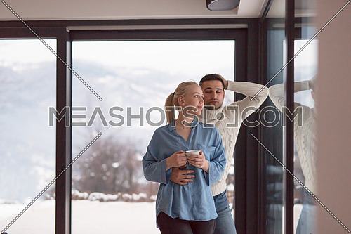 romantic young couple enjoying tea by the window on cold winter evening at home