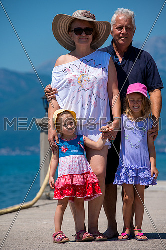 portrait of  happy grandparents with cute little granddaughters standing by the sea during Summer vacation  Healthy family holiday concept