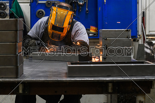 Professional welder performs work with metal parts in factory, sparks, and electricity. Industry worker banner. High quality photo