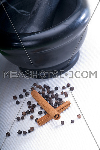 black stone mortar and pestel with cinnamon and pepper