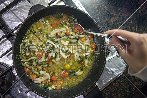 female hand stirring Mussel Seafood Soup in a hot pan