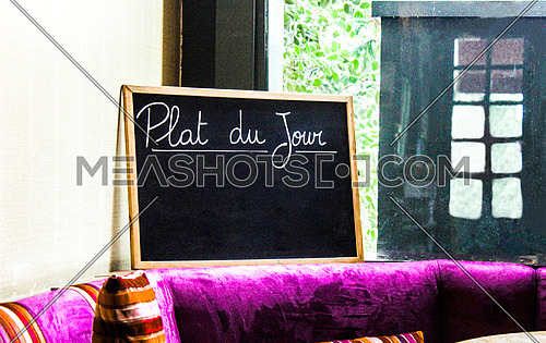A black chalk board inside a restaurant written on it plat du jour
