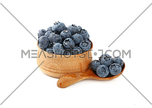 Close up portion of fresh washed blueberry berries with water drops in one rustic natural wooden scoop spoon and bowl isolated on white, high angle view