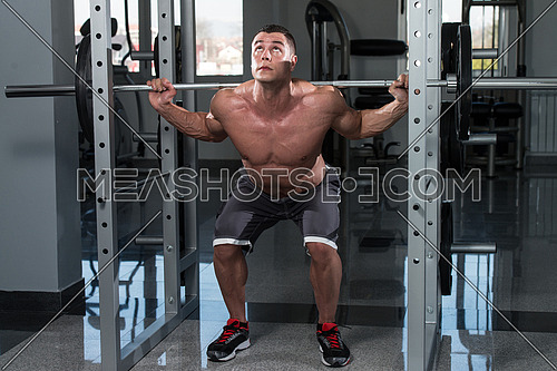 Young Man Performing Barbell Squats - One Of The Best Bodybuilding Exercise For Legs