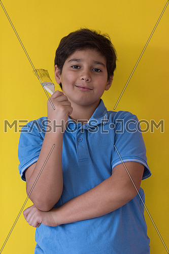 Portrait of a young boy painter with a brush in his hand in front of colored background