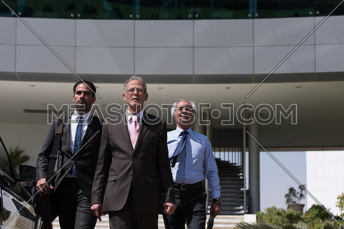 A group of business executives walking in front of a corporate building