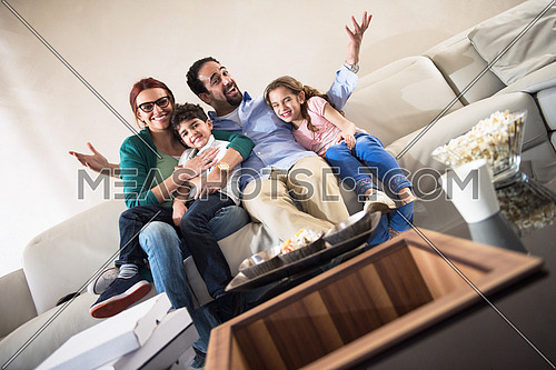 happy middle eastern family enjoys spending a quality time with the kids on the sofa with movies and popcorn