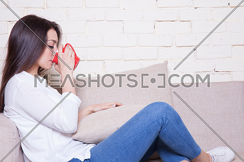 A girl sitting on a couch drinking coffee