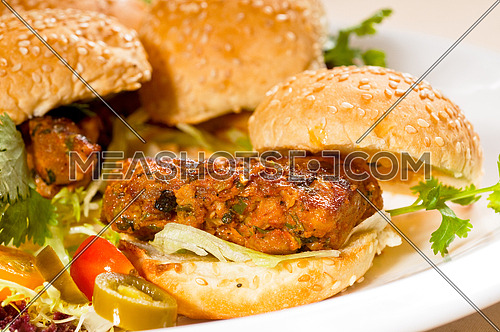 four fresh and delicious mini chicken burgers on a plate ,close up