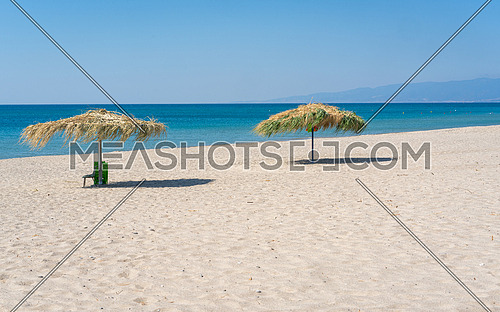 Two beach umbrela on sandy beach, mediterranean sea, Calabria Italy.