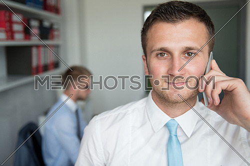 Happy Young Business Man Talking On Telephone In Modern Office Behind Him Sitting His Colleague