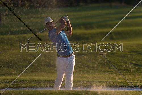 golfer shot ball from sand bunker at golf course with beautiful sunset in background