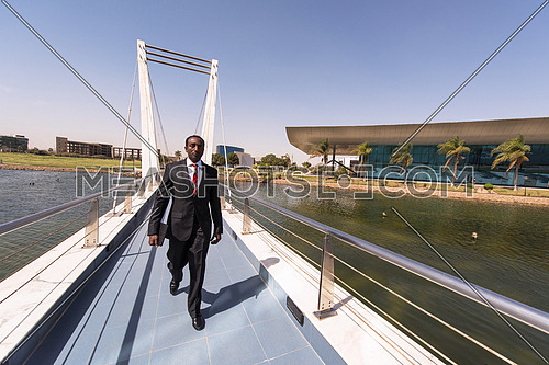 african businessman walking across modern footbridge