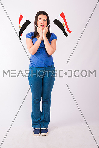 Young lady standing and holding two small egyptian flags on white background.