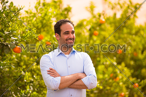 Portrait of a young middle eastern man on the farm tangerine with a smile on his face