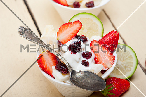 fruit and yogurt salad healthy breakfast over white wood table