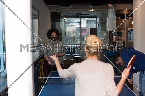 group of young startup business people playing ping pong tennis at modern creative office
