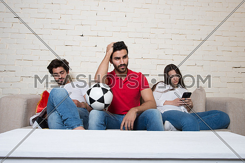 A group of middle eastern  friends watching a football game in the living room