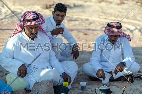 Bedouin Males wearing traditional clothing, sitting and making tea at Ain Hodouda area in Sinai at day.