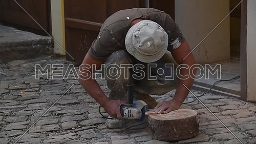 Close up of working man cutting and shaping ceramic tile with angle grinder, low angle view