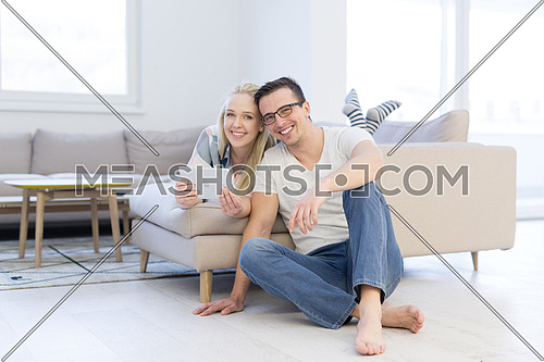 Young couple relaxing at  home using tablet computers reading in the living room on the sofa couch.