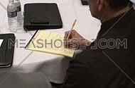 Close shot for a business man wearing a suit and taking notes.