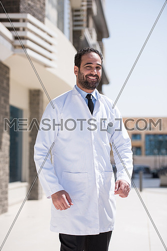 middle eastern young doctor portrait in front of modern hospital