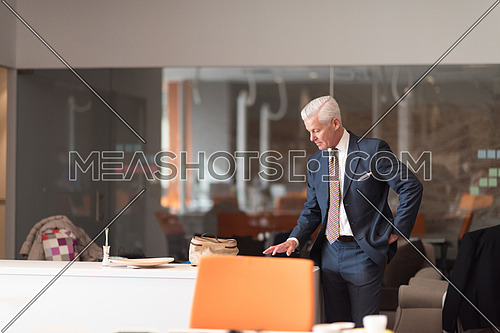 senior business man reading reports on tablet computer at modern office interior