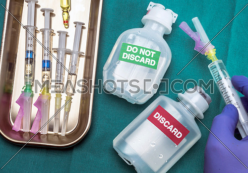 Nurse preparing parenteral medication discard and not discard, syringes with medication on tray, conceptual image horizontal composition