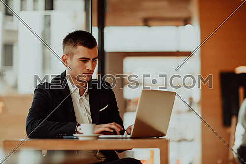businessman sitting at the cafeteria with a laptop and smartphone. Businessman texting on smartphone while sitting in a pub restaurant. Businessman working and checking email on the computer.