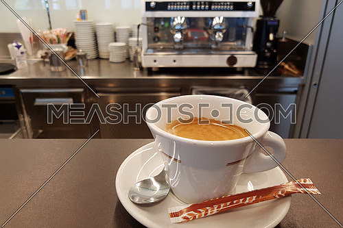 Good morning hot cup of coffee at the barin front of a blurred espresso machine bacground