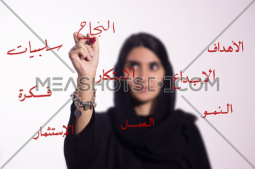 Arabian middle eastern business woman writing with a marker on virtual screen in arabic different words "sucess"
isolated on white background